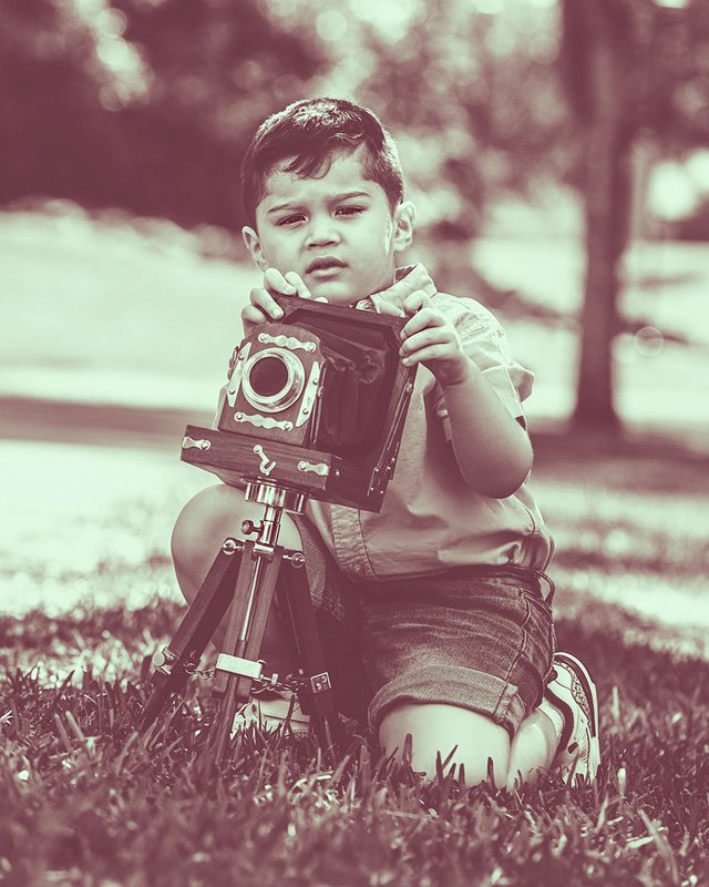 Child posing with a vintage camera outdoors.