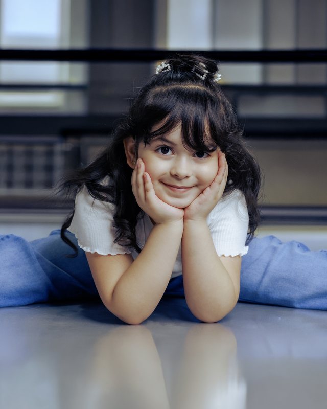 Child resting her chin on her hands beside a piano.