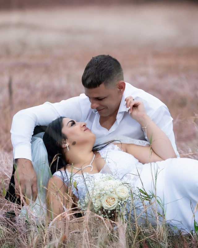 Bride and groom resting together in a grassy field
