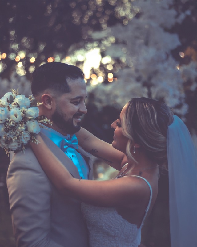 Bride and groom embracing beneath evening lights