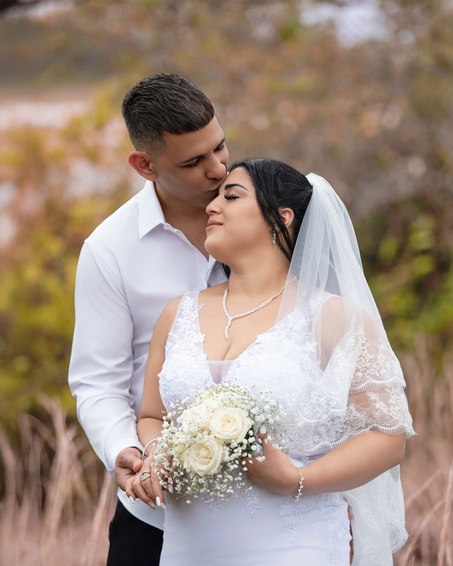 Groom kissing the bride on her forehead outdoors