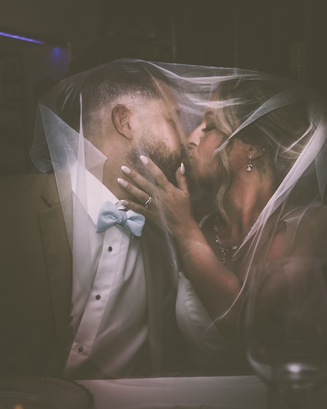 Bride and groom kissing beneath a veil