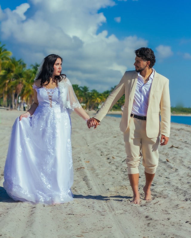 Bride and groom holding hands on a sandy beach