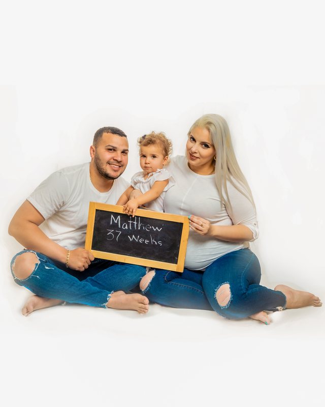 Family seated together against a white background, holding a chalkboard.